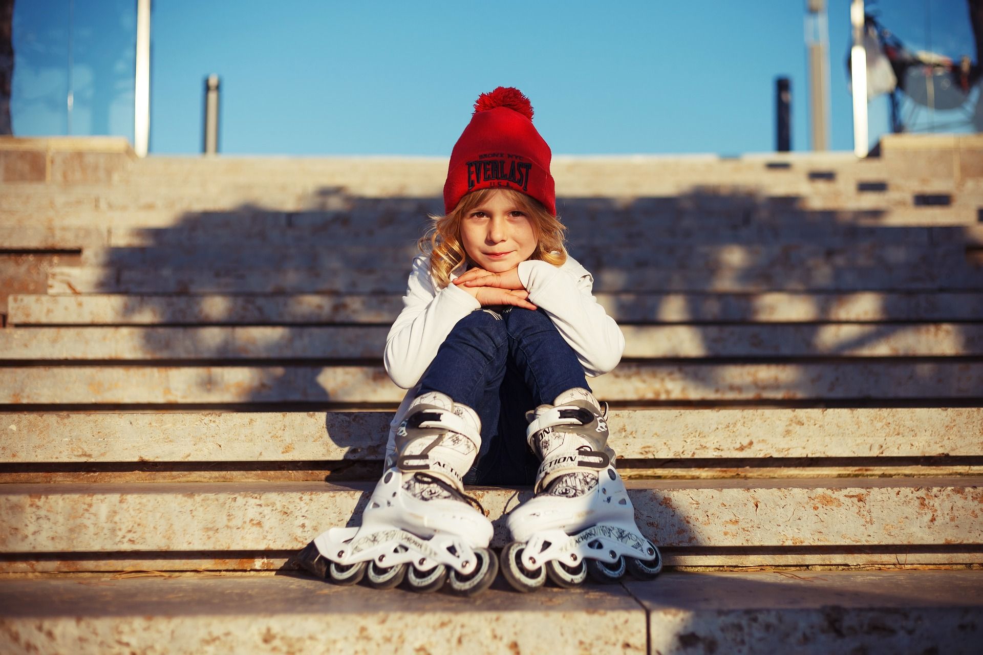 Young girl sitting down outdoors wearing inline skates