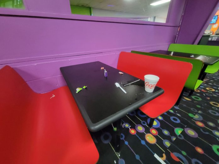 ply mold black snack bar table top with red bench with a styrofoam soft drink cup, spoon, straw, and liquid mess