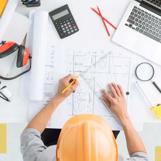 Person in hard hat working on a blueprint