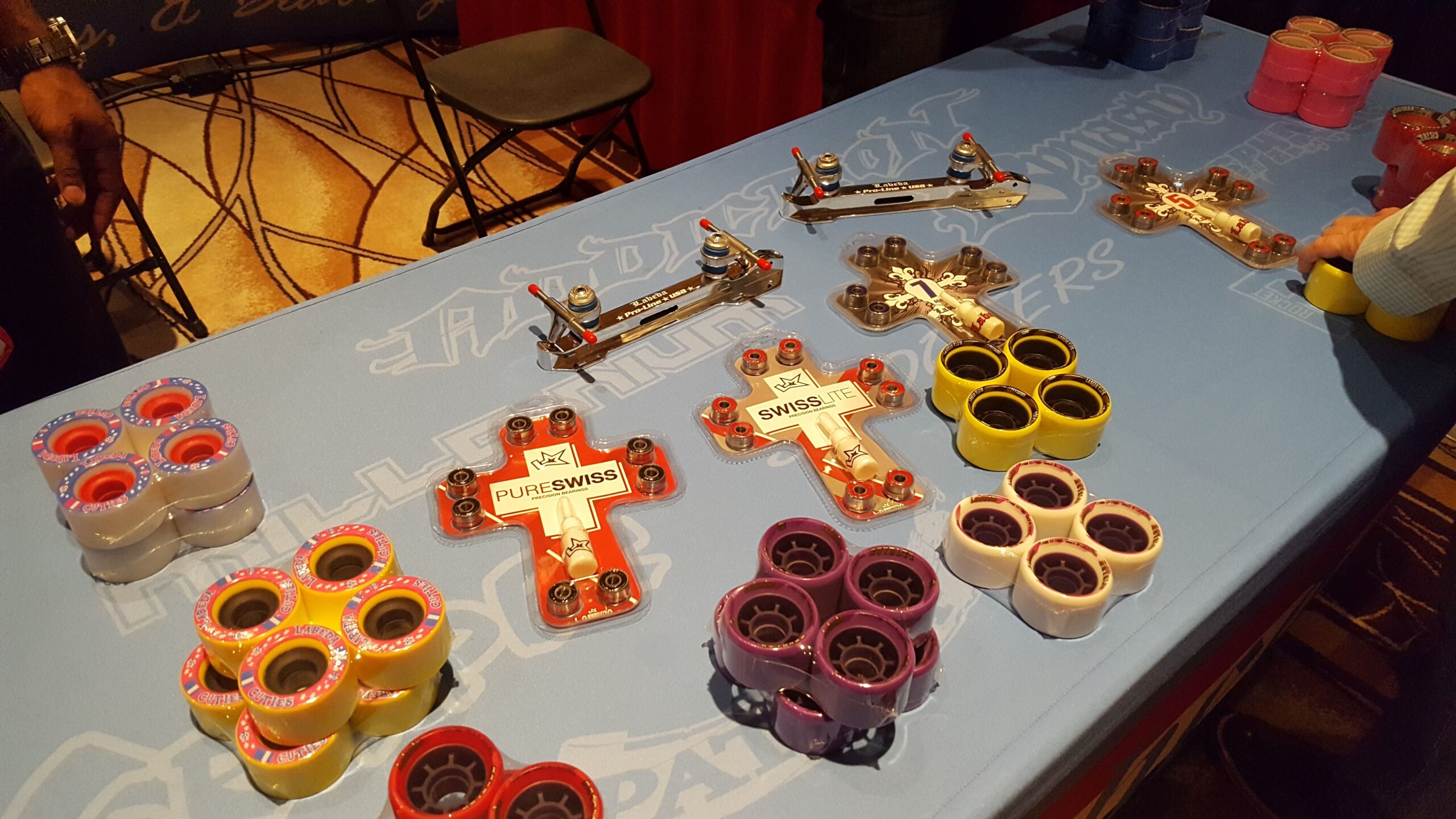 A table displaying packaged roller skate wheels, bearings, and quad roller skate plates.